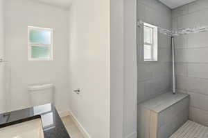 Full bath featuring tiled shower, vanity, and light tile patterned floors