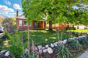 View of front of house featuring brick siding, a front yard, a chimney, and a mountain view
