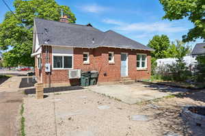 Back of property with brick siding, a shingled roof, a chimney, entry steps, and a patio area