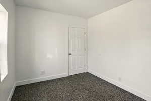 Unfurnished room with baseboards and dark colored carpet