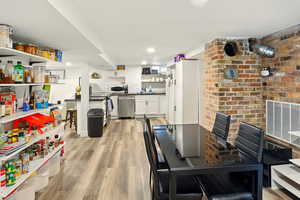 Dining space with light wood-style flooring, brick wall, and recessed lighting