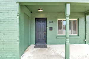 Doorway to property with brick siding and a porch