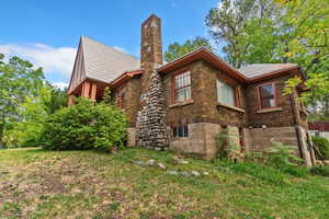 Rear view of property with a chimney and brick siding