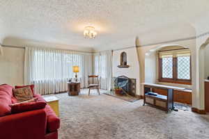 Carpeted living area with a textured ceiling and arched walkways