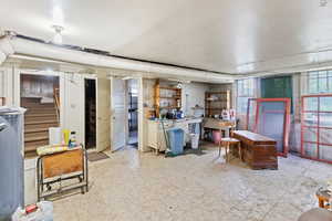 Basement featuring light flooring, stairway, and water heater