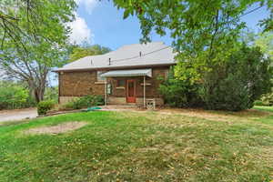 Back of house with a lawn and brick siding
