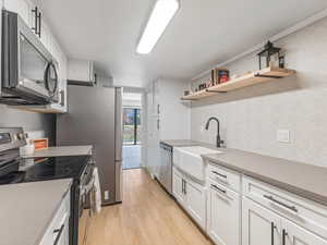 Kitchen featuring appliances with stainless steel finishes, white cabinets, light wood-type flooring, and open shelves