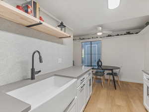 Kitchen featuring white cabinets, light wood finished floors, open shelves, ceiling fan, and light stone countertops