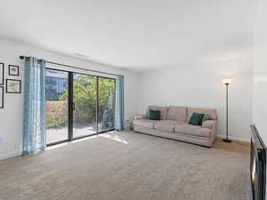 Living area with light colored carpet and sliding glass doors to a private back patio.