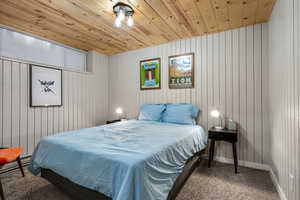 Unit 1b, carpeted bedroom featuring wooden walls and wooden ceiling