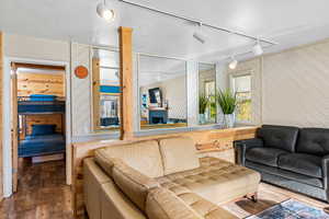 Living area featuring rail lighting, wood walls, and wood finished floors