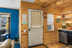 Kitchen with open shelves, dishwasher, wood walls, light wood-style flooring, and light countertops