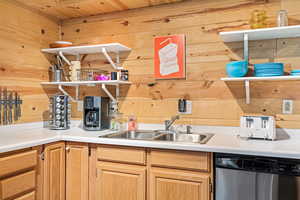 Unit 1b, kitchen featuring open shelves, stainless steel dishwasher, wooden walls, and light countertops