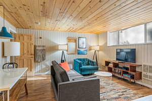 Unit 1b, living room featuring wood finished floors, wood walls, and wood ceiling