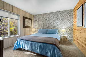 Bedroom with wooden walls and carpet floors