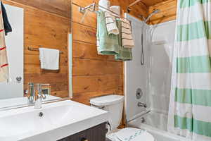 Unit 1b, full bath featuring wood walls, shower / bath combination with curtain, and vanity