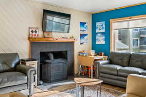 Living area with wood finished floors, wooden walls, TV, and a wood burning stove