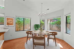 Virtually staged, Dining space featuring light wood-style floors, a chandelier, and high vaulted ceiling