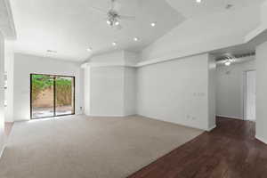 Unfurnished living room featuring wood finished floors, a ceiling fan, vaulted ceiling, recessed lighting, and carpet