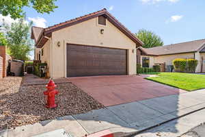 View of front of house with stucco siding, a garage, driveway, a gate, and a tile roof
