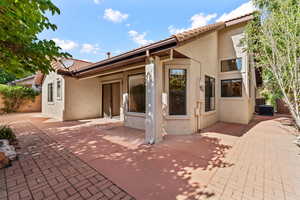 Back of house with stucco siding and a tiled roof