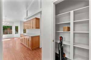 Interior space with light wood-style flooring, light countertops, a chandelier, hanging light fixtures, and light brown cabinets