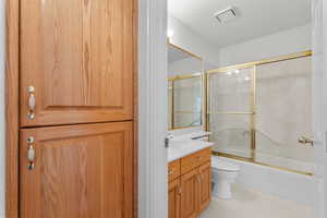 Full bathroom featuring combined bath / shower with glass door, vanity, and light tile patterned floors