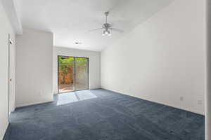 Empty room featuring carpet, ceiling fan, and vaulted ceiling
