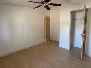 Unfurnished bedroom with light wood-style floors, a ceiling fan, and a closet