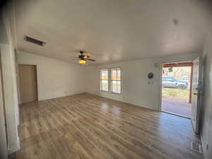 Unfurnished living room with ceiling fan, wood finished floors, and lofted ceiling