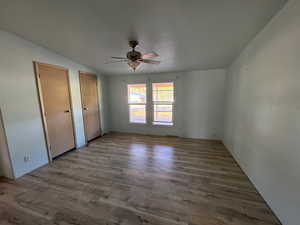 Unfurnished bedroom with multiple closets, NEW LVP finished floors, ceiling fan, and lofted ceiling