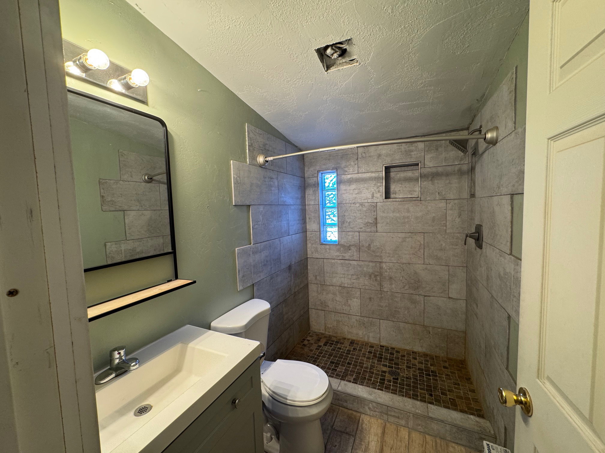 Full bathroom with vanity, a stall shower, a textured ceiling, a textured wall, and LVP finished floors