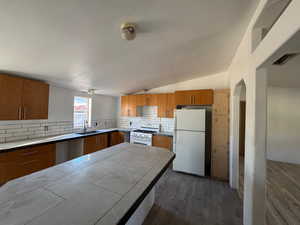 Kitchen with lofted ceiling, white appliances, dark wood-style flooring, a textured ceiling.