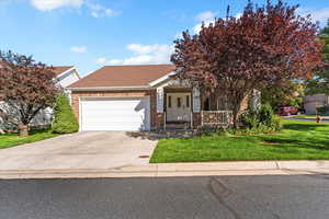 View of front of property featuring a porch, a front lawn, a shingled roof, and concrete driveway