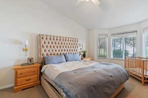 Carpeted bedroom with vaulted ceiling and ceiling fan