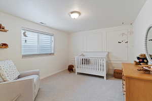 Bedroom featuring a crib and light carpet