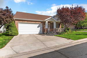 Ranch-style home with a front yard, brick siding, driveway, roof with shingles, and an attached garage