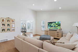 Living room featuring hardwood / wood-style floors, recessed lighting, and high vaulted ceiling