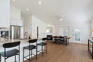 Kitchen featuring a peninsula, white cabinets, freestanding refrigerator, light wood-style floors, and light stone countertops