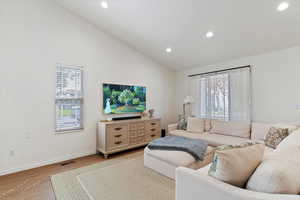 Living area with lofted ceiling, wood finished floors, and recessed lighting