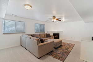 Living area featuring light colored carpet, a fireplace, and ceiling fan