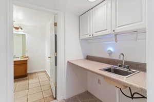 Laundry room featuring light tile patterned floors and a sink