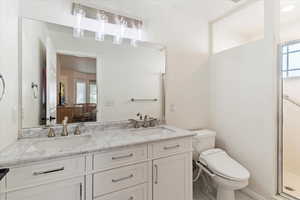 Ensuite bathroom featuring double vanity, a shower stall, and light tile patterned flooring