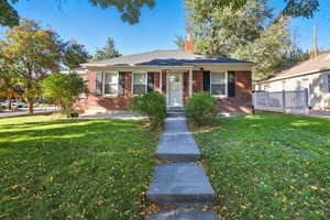 View of front of house with a front lawn, brick siding, and covered porch