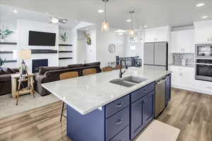 Kitchen featuring blue cabinetry, a kitchen bar, open floor plan, white cabinetry, and recessed lighting