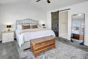 Bedroom with a barn door, carpet flooring, lofted ceiling, a ceiling fan, and connected bathroom