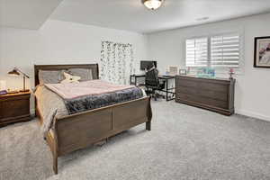 Bedroom featuring light carpet and an office area