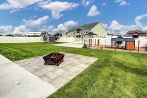 Fenced backyard with a patio, a fire pit, a shed, and a residential view