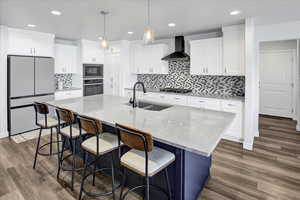 Kitchen featuring stainless steel appliances, white cabinetry, light stone countertops, decorative light fixtures, and recessed lighting