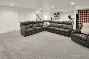 Carpeted living area with recessed lighting and baseboards